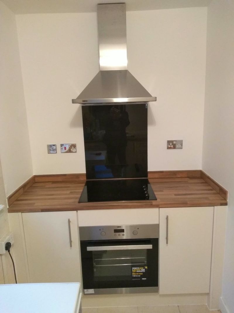 New kitchen with a built-in oven, hob, extractor hood and wood worktop