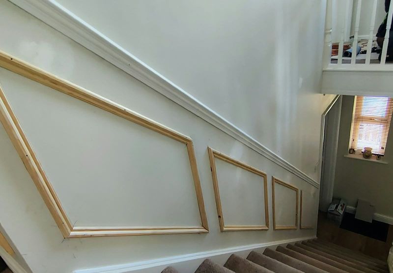 Staircase wall finished with white decorative panel moulding
