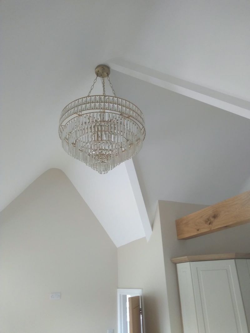 Finished vaulted ceiling painted white, with a crystal chandelier